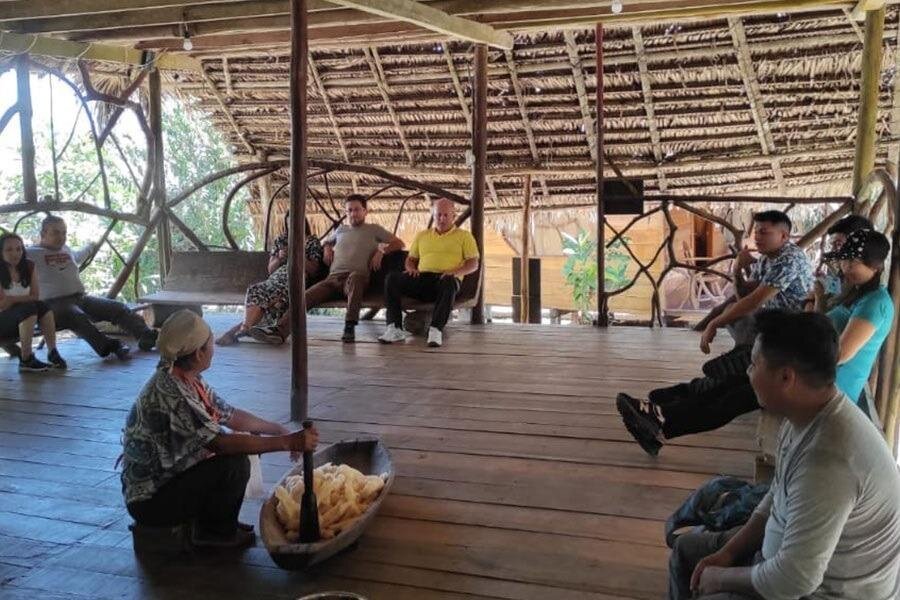 A group of people watch a class delivered by an indigenous person in a hut in the Amazon near Puyo, Ecuador