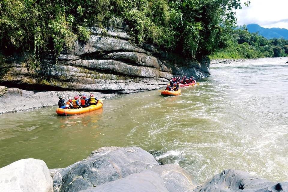 Two yellow rafts on calm water on a river in the Amazon near Puyo, Ecuador