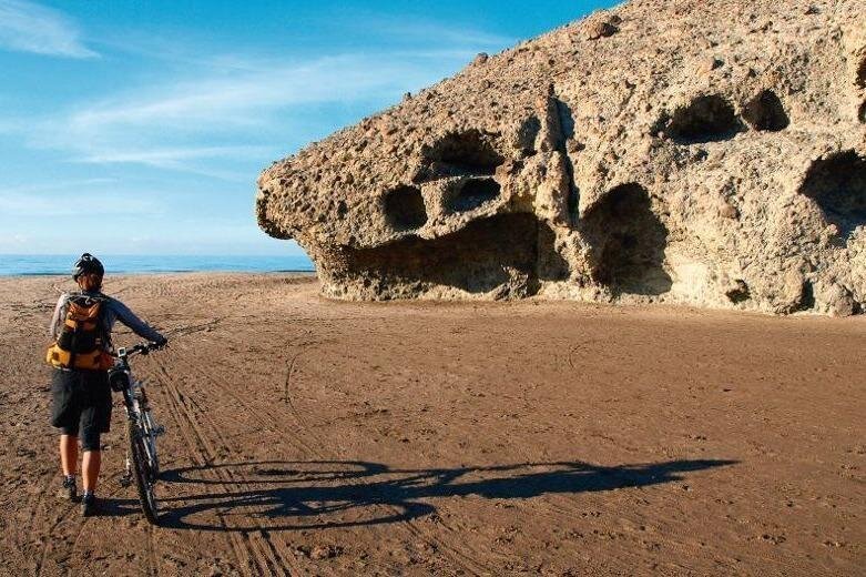 A woman walks her bike along a beach at Machalilla, Puerto Lopez, Ecuador