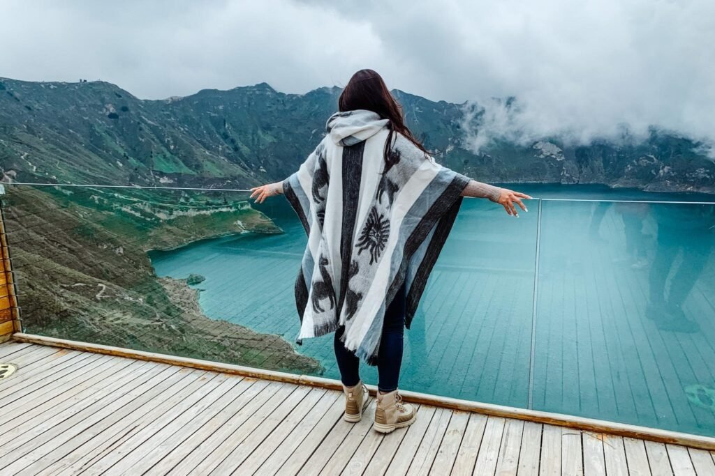 A woman in a dark poncho looks out over Quilotoa Lake, Ecuador