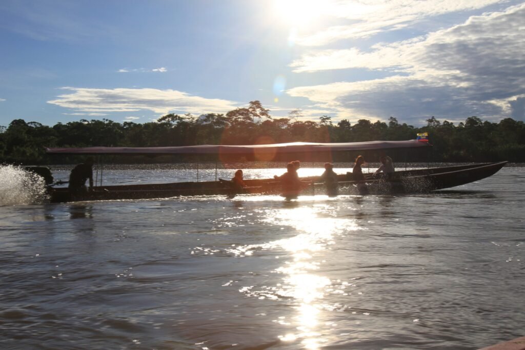 A river boat sails through the sun along a tributary in the Amazon, Ecuador