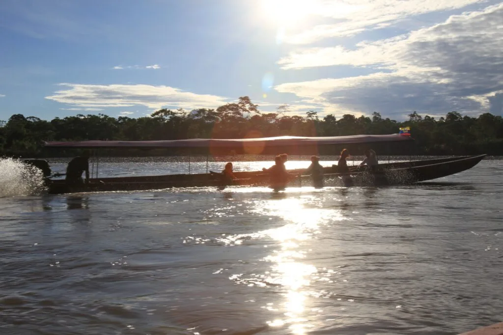 A river boat sails through the sun along a tributary in the Amazon, Ecuador