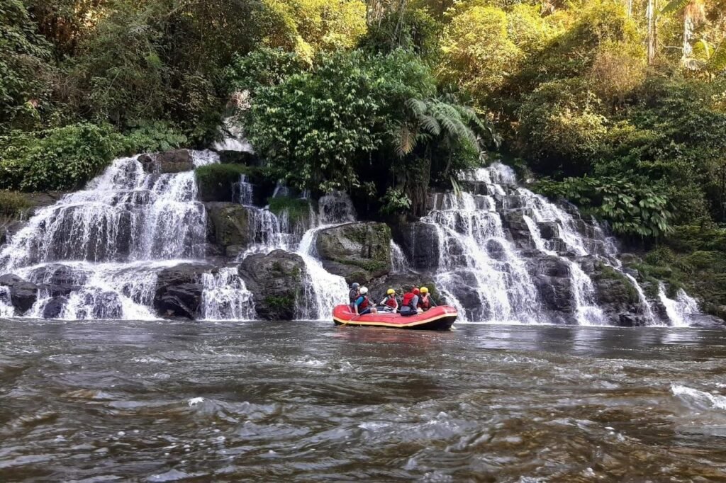 A rubber raft floats beside a large cascade near Tena, Ecuador