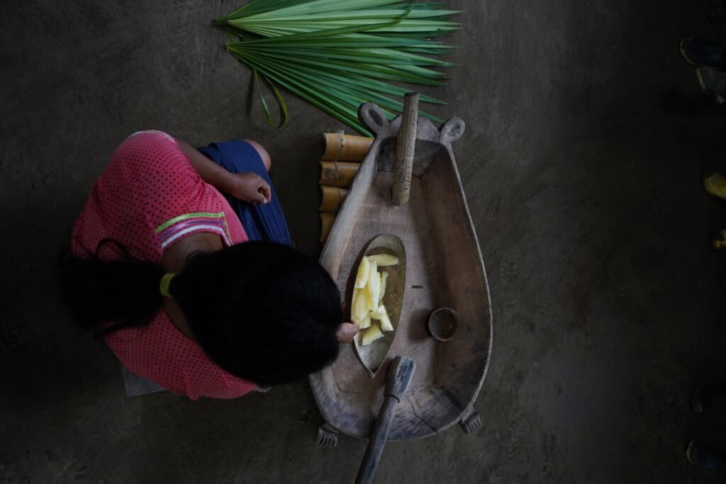 An overhead shot of a woman sitting cross legged preparing food in the Amazon, Ecuador