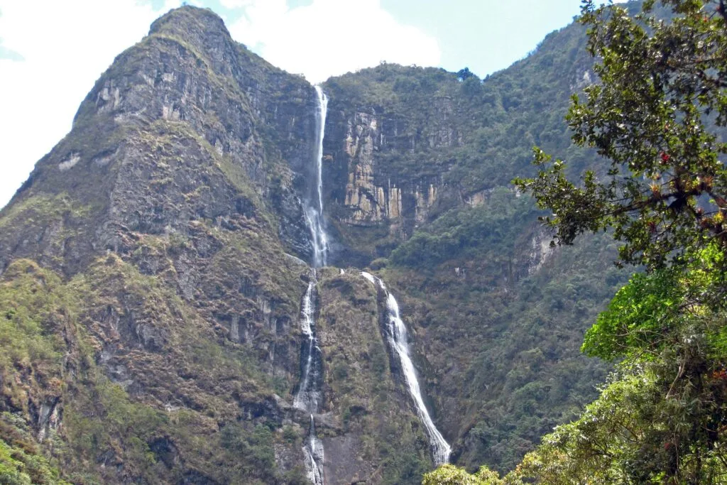 A huge waterfall tumbles oevr a giant green cliff in the Andes near Cuenca, Ecuador
