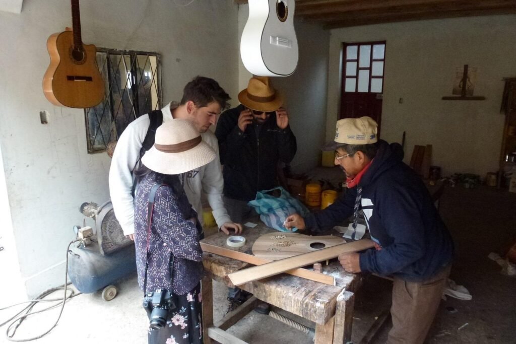 A group of people watch a man make a guitar in San Bartolome, near Cuenca, Ecuador