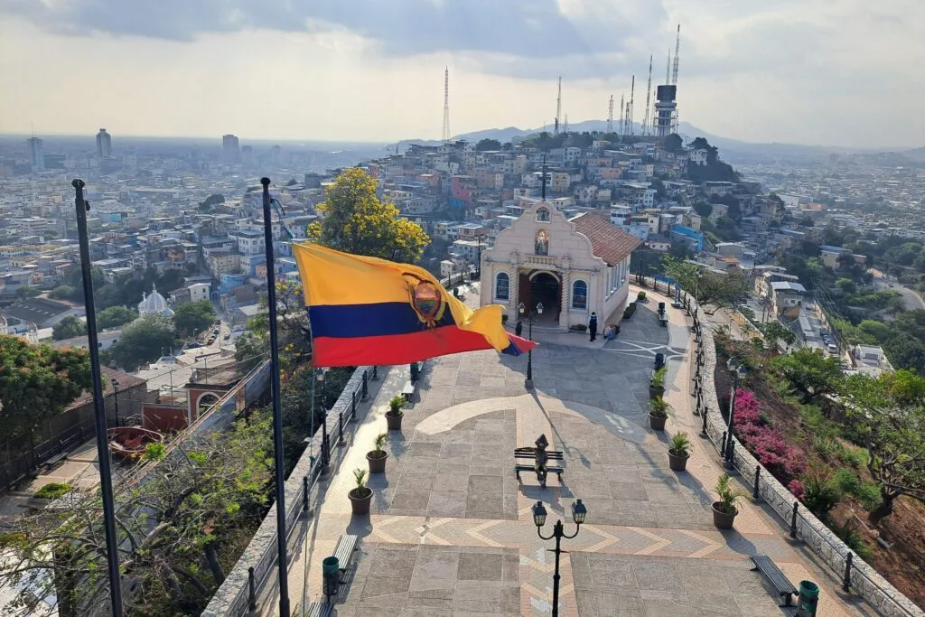 The Ecuadorian flag, a small church and the multi-coloured houses of Las Peñas in Guayaquil, Ecuador