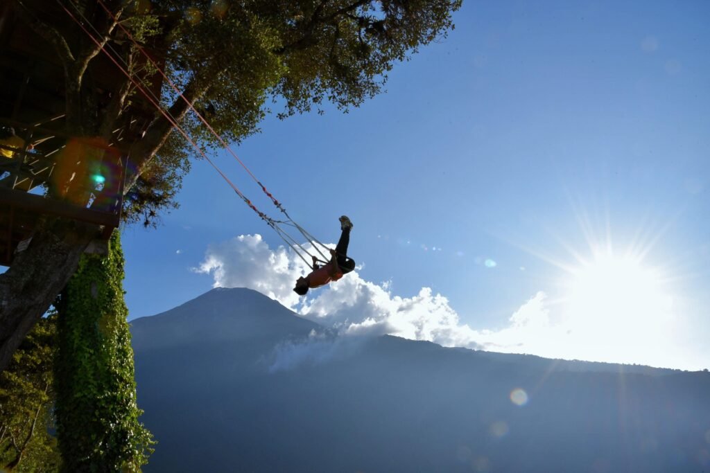 A person swings from the Casa del Arbol in front of Volcán Tungurahua in Baños, Ecuador