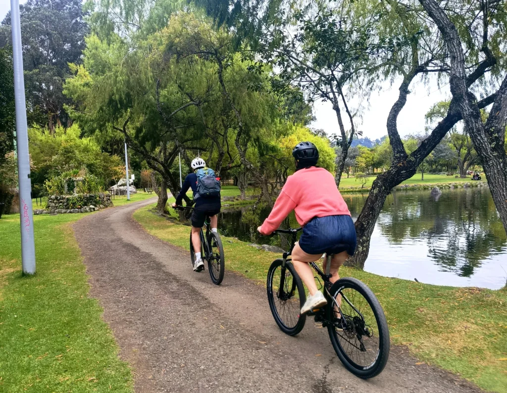 People ride bikes along a path beside the Tomebamba River in Cuenca, Ecuador