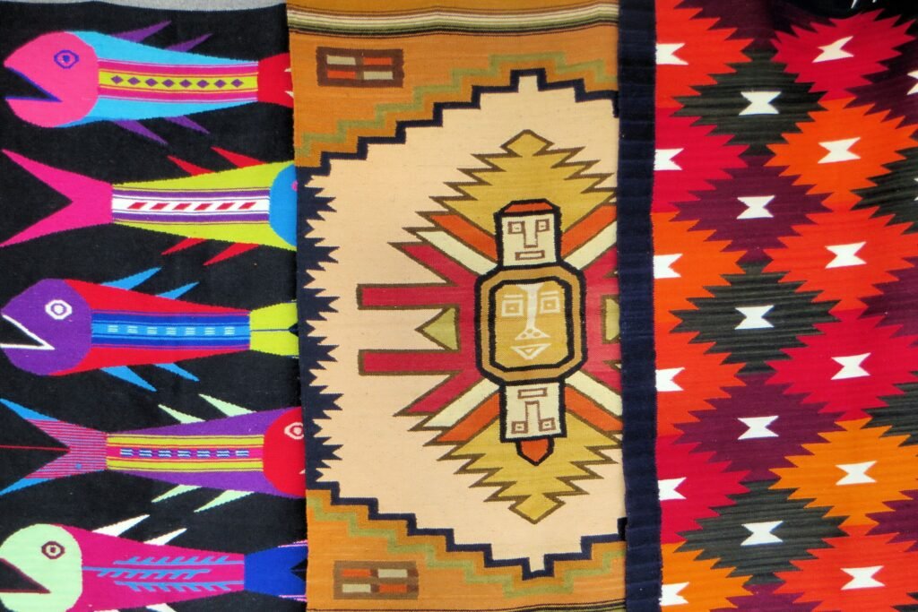 Three brightly coloured ponchos on sale in a plaza market in Otavalo, Ecuador.