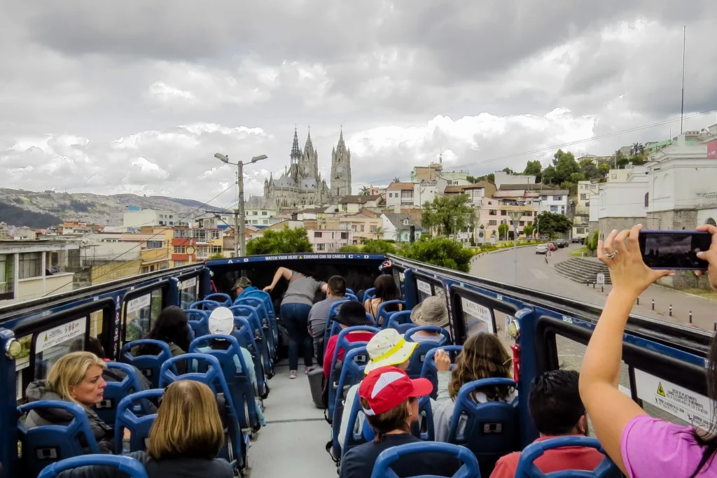 People look at the Basílica del Voto Nacional from the top deck of a tour bus in Quito, Ecuador