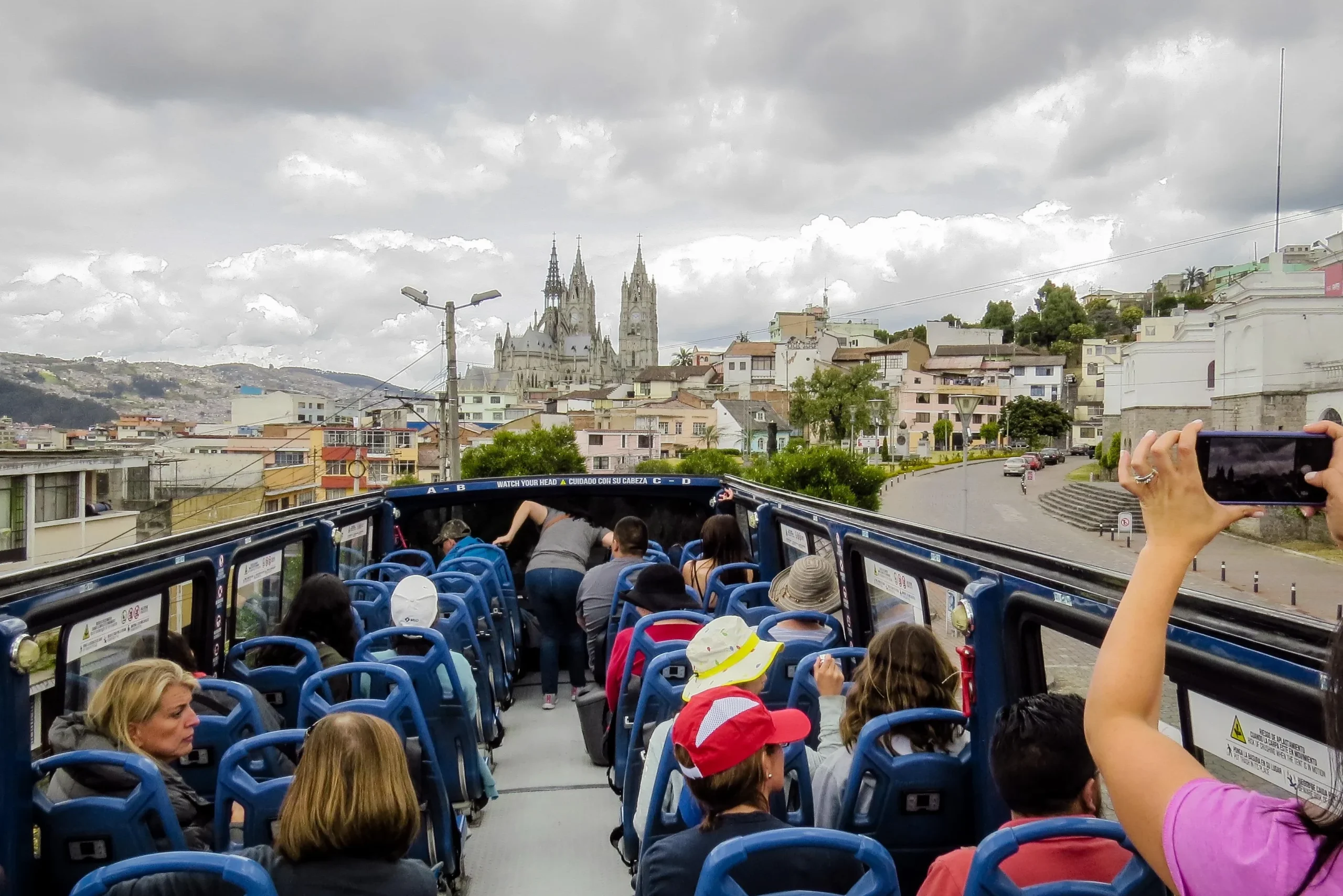 La gente contempla la Basílica del Voto Nacional desde la cubierta superior de un autobús turístico en Quito, Ecuador