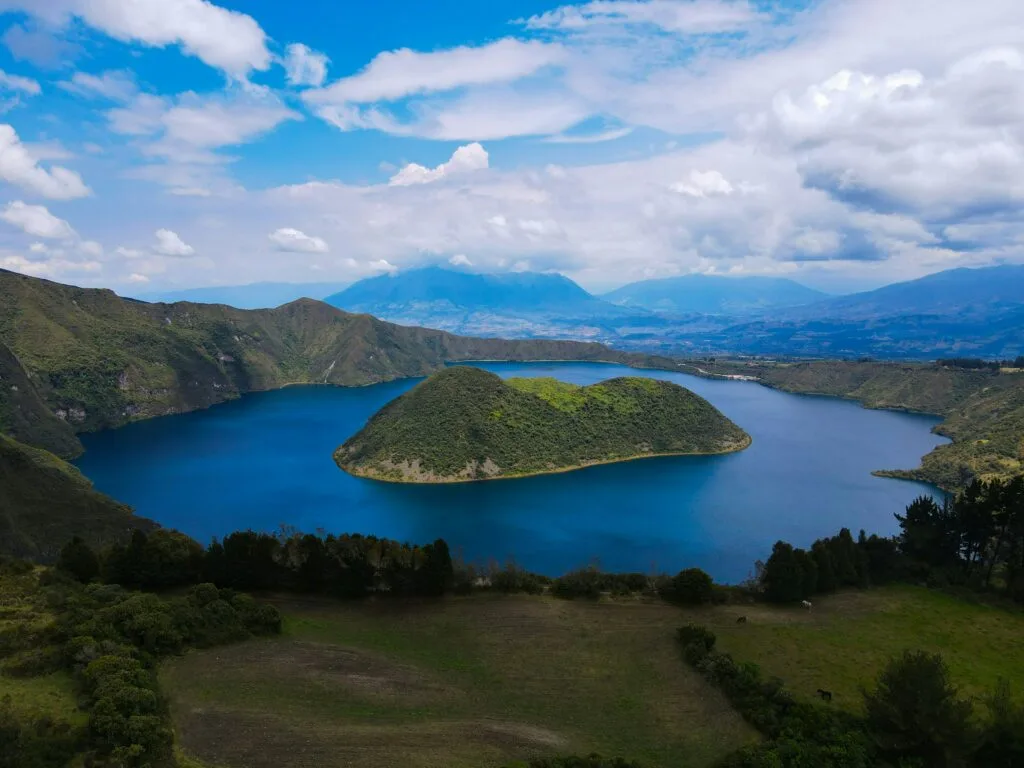A wide shot of Laguna de Cuicocha showing the island, caldera and volcanos behind, near Cotocachi, Ecuador