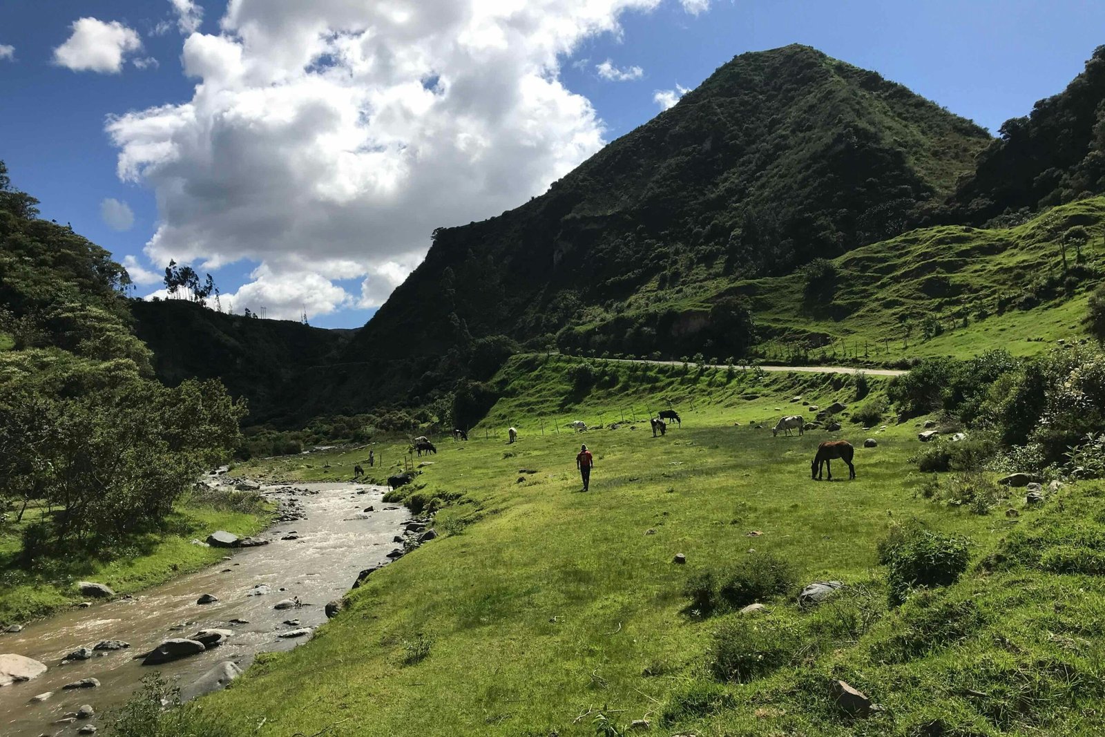 A river flows through green meadows and mountains of the Isinliví, Sigchos, Quilotoa Loop, Ecuador.