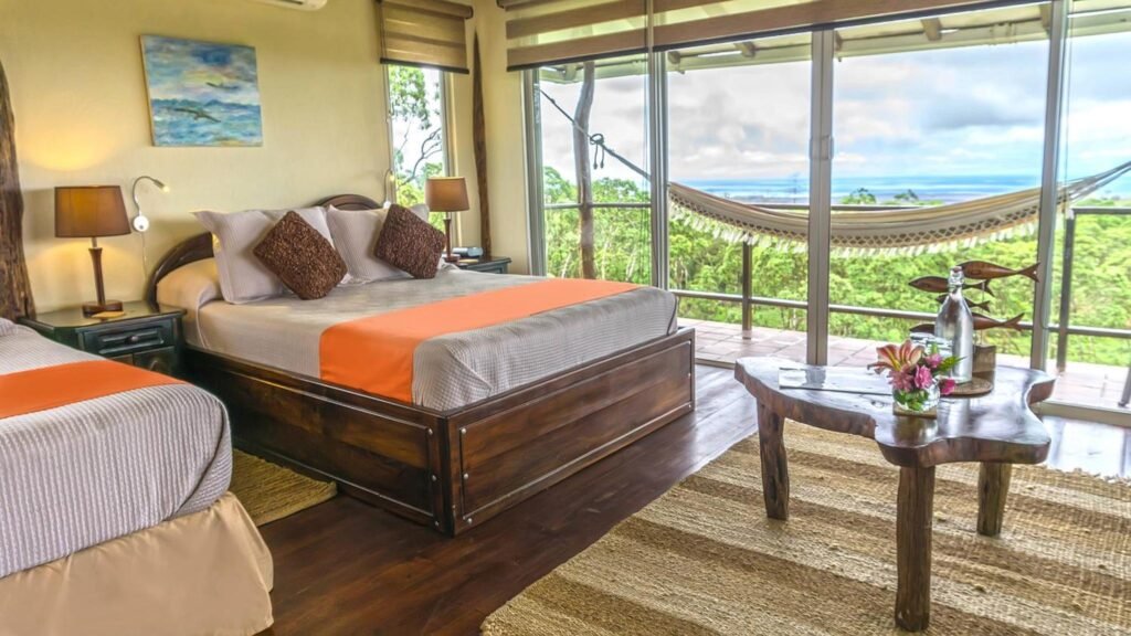Una habitación del Hotel Boutique Semilla Verde con cama de matrimonio, balcón, hamaca y árboles verdes de las Galápagos