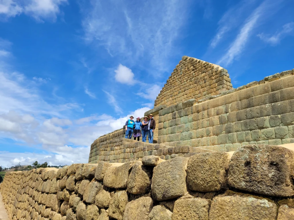 A small group of people stand outside the Temple of the Sun in Ingapirca, Ecuador