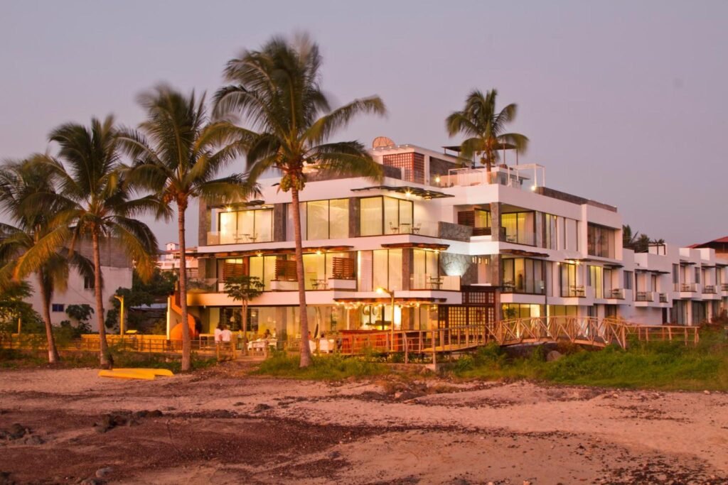 El Golden Bay Hotel, un edificio blanco de tres plantas situado en una playa rodeada de palmeras en Puerto Baquerizo Moreno, San Cristóbal, Galápagos, Ecuador