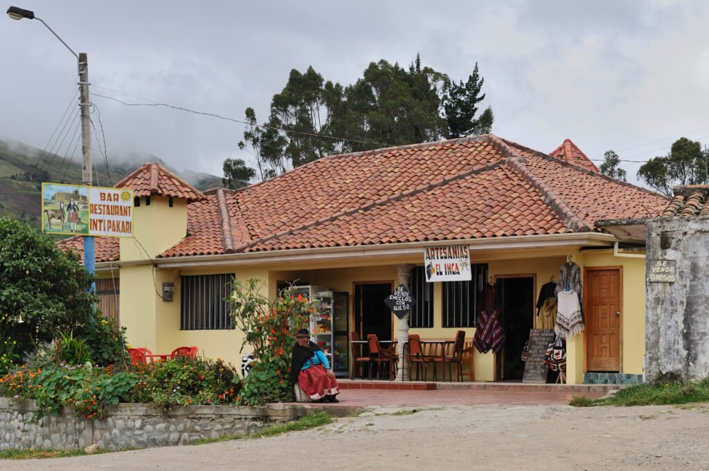 An old lady sits outsdie a restaurant in Cañar, near Ingapirca, Ecuador