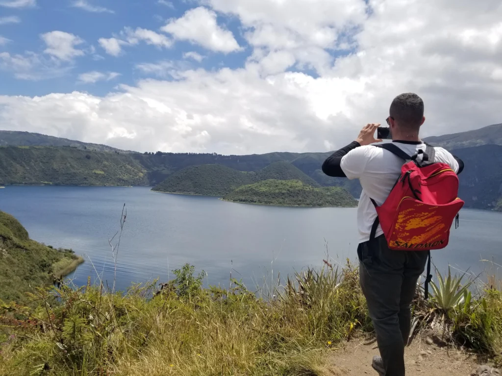 A man takes a photo of Lake Cuicocha on a sunny day near Cotocachi and Otavalo, Ecuador