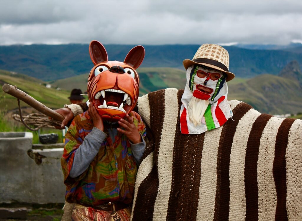 Two men wear masks and traditional dress during a festival in Guangaje, Ecuador