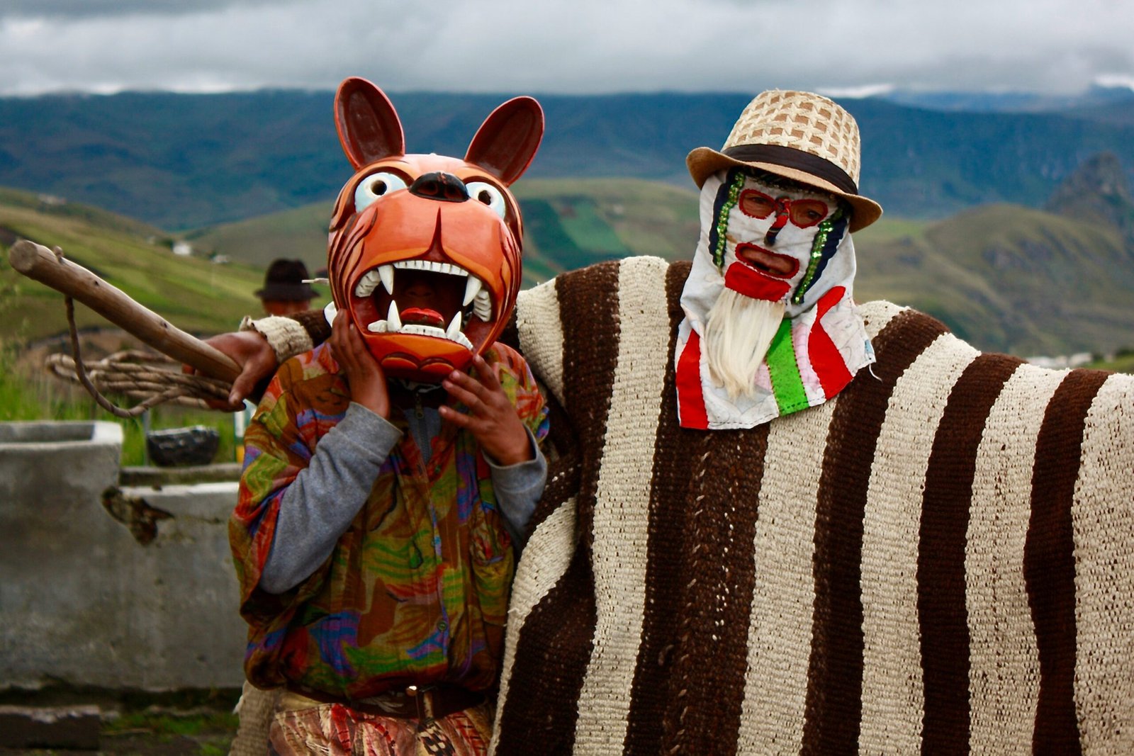 Two men wear masks and traditional dress during a festival in Guangaje, Ecuador