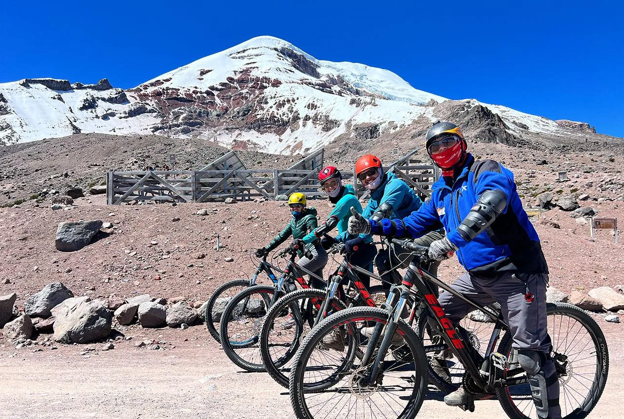 A group of people sit on mountain bikes in front of Chimborazo, Ecuador