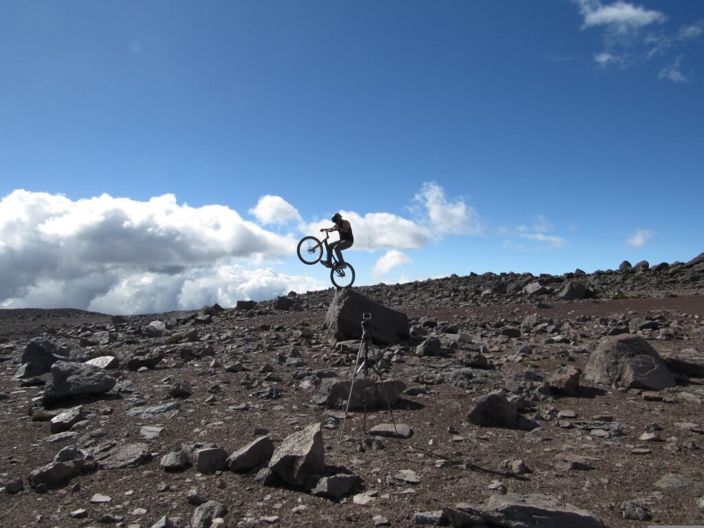 A cyclist wheelies on the volcanic rocks and scree of Chimborazo, Ecuador