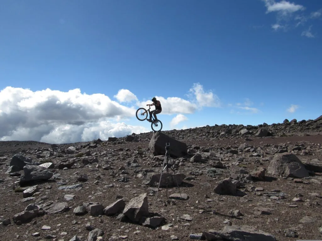 A cyclist wheelies on the volcanic rocks and scree of Chimborazo, Ecuador