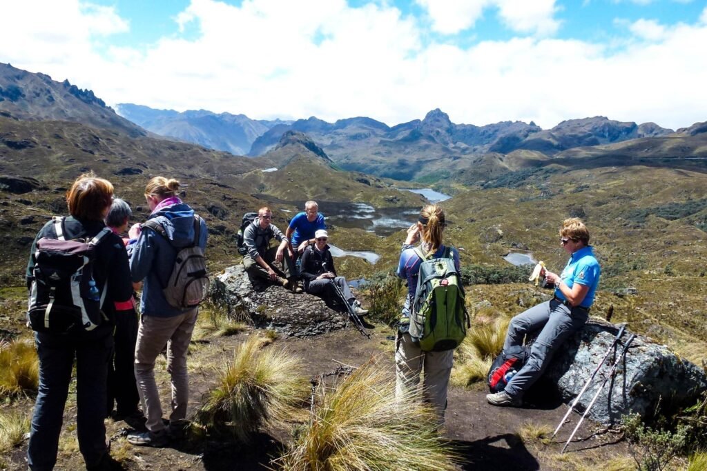 A group of people in hiking gear eat snacks in Cajas National Park, Cuenca, Ecuador