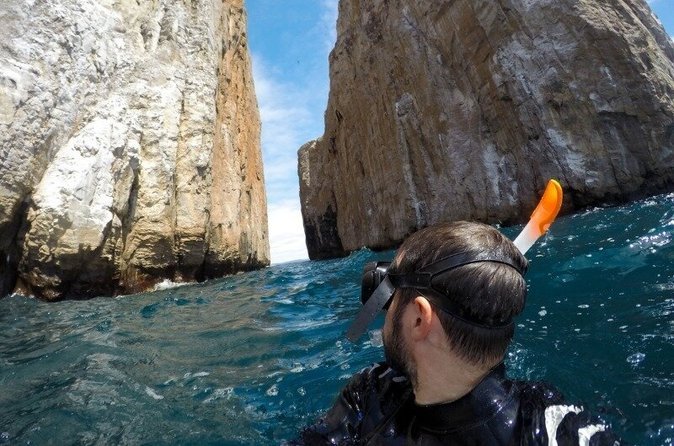 A snorkeller swims in deep blue water between the huge crack in Kicker Rock, Leon Dormido, San Cristobal, Galapagos, Ecuador