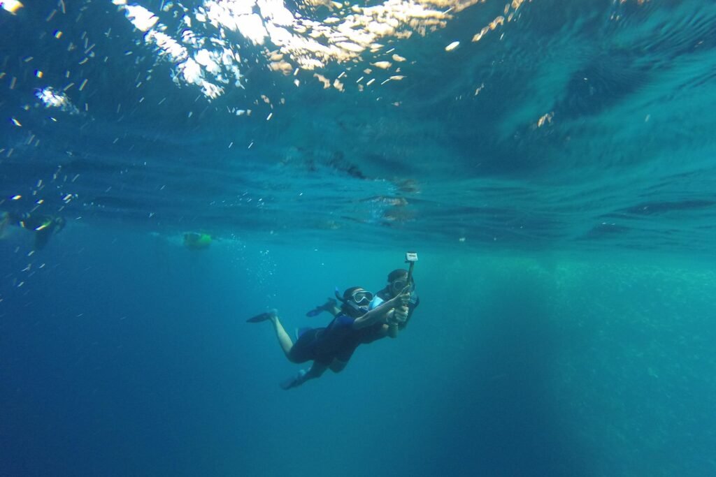 Two snorkellers dive under the water with a GoPro near San Cristobal, Galapagos, Ecuador