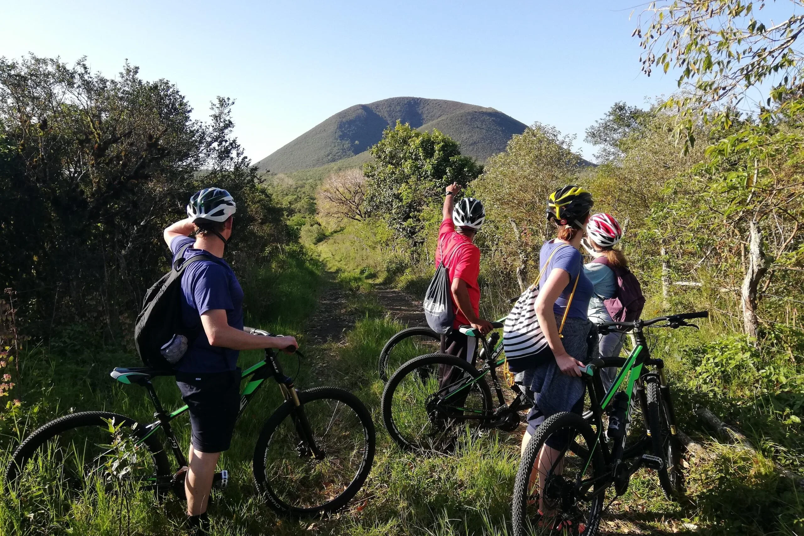 People on bikes point at a small conical volcano on Floreana Island, Galapagos, Ecuador