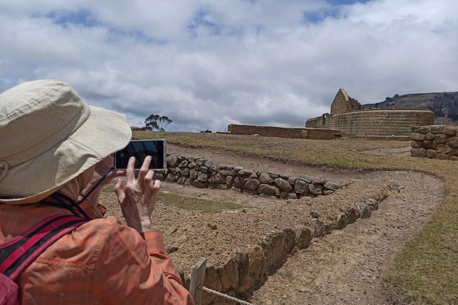 A person takes a picture of the Temple of the Sun with their phone at Ingapirca, Ecuador